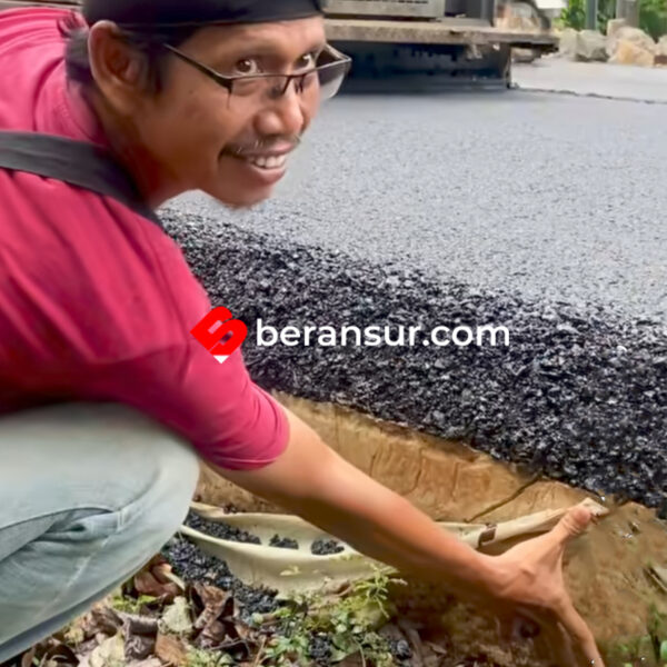 Seorang Pria yang Memperlihat Aspal Setebal Sejengkal